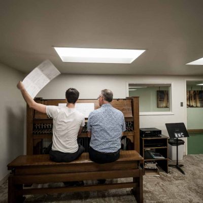 Beiaardiers Frans Haagen en Joey Brink studeren Ripple Effects op het studieklavier in het carillonkantoor in de kelder van Rockkefeller Memorial Chapel.