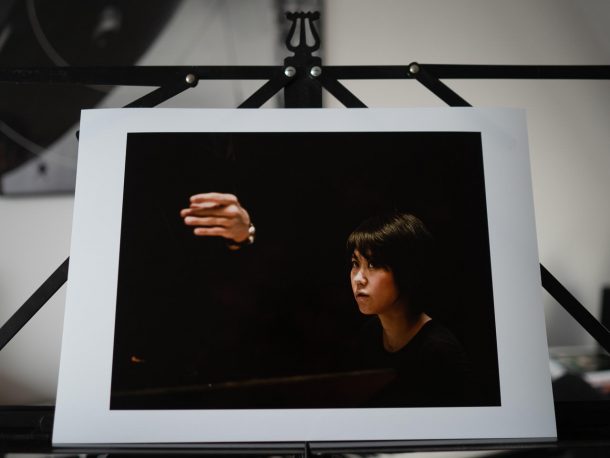Print van pianiste Yuja Wang die tijdens een repetitie kijkt naar de hand van een dirigent